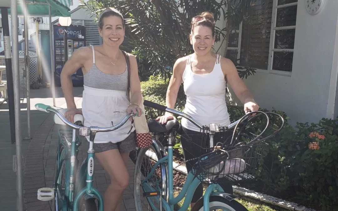 Two women with beach bikes, smiling at the camera.